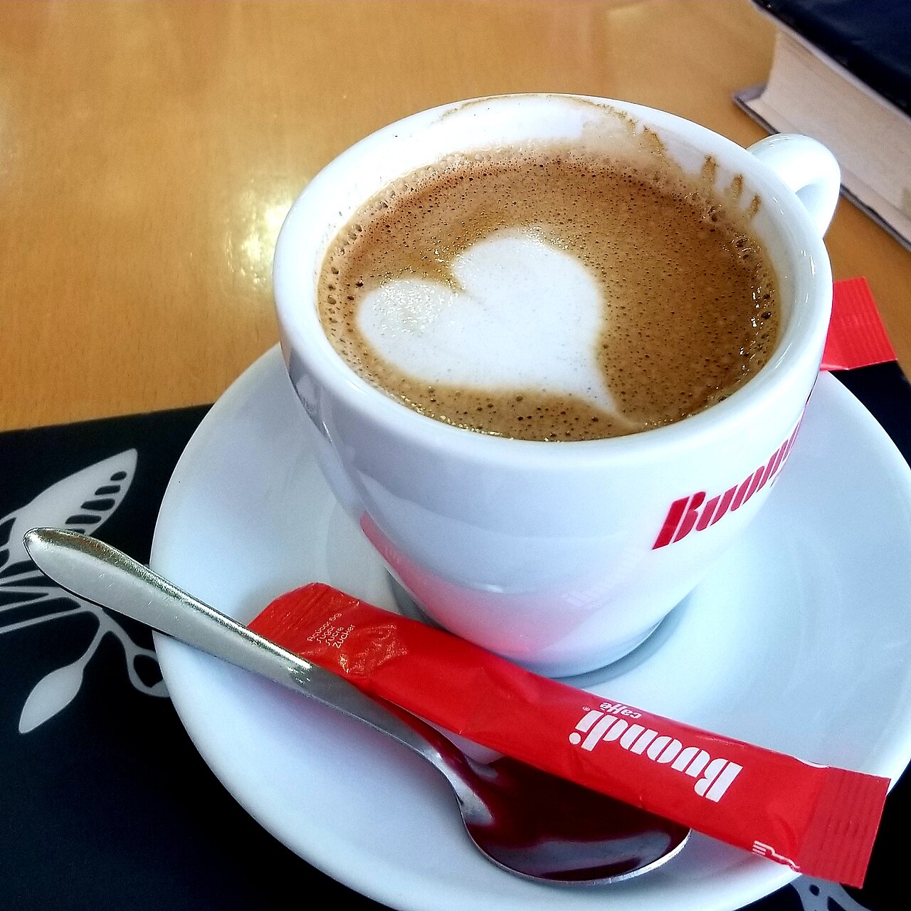 Latte with poured latte art and a milk frother beside it